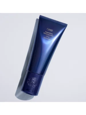 Toma profesional de la Oribe Supershine Moisturizing Cream recostada sobre fondo gris claro.