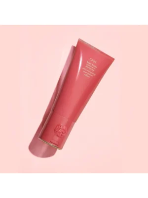 Vista en ángulo del envase de Oribe Bright Blonde Conditioner for Beautiful Color de 200 ml sobre un fondo rosado con sombras estéticas