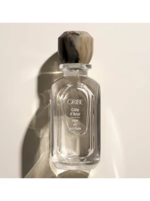Frasco de cristal de Oribe Côte d’Azur Eau de Parfum de 75 ml con tapón artesanal veteado en tonos piedra y marrón.