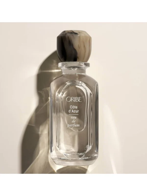 Frasco de cristal de Oribe Côte d’Azur Eau de Parfum de 75 ml con tapón artesanal veteado en tonos piedra y marrón.