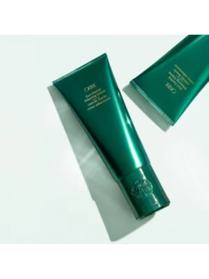 Composición estética de dos envases de Oribe Curl Control Silkening Creme sobre fondo blanco con iluminación lateral