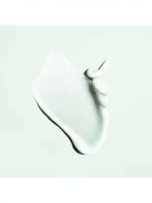 Muestra de la textura en crema blanca y sedosa de Oribe Curl Control Silkening Creme sobre fondo verde menta