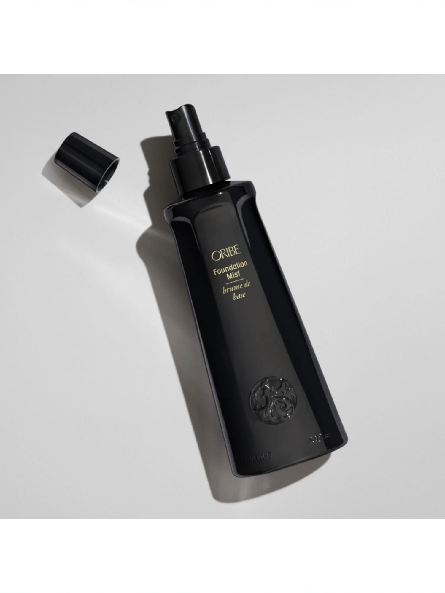 Detalle de Oribe Foundation Mist con el tapón abierto mostrando el pulverizador de precisión