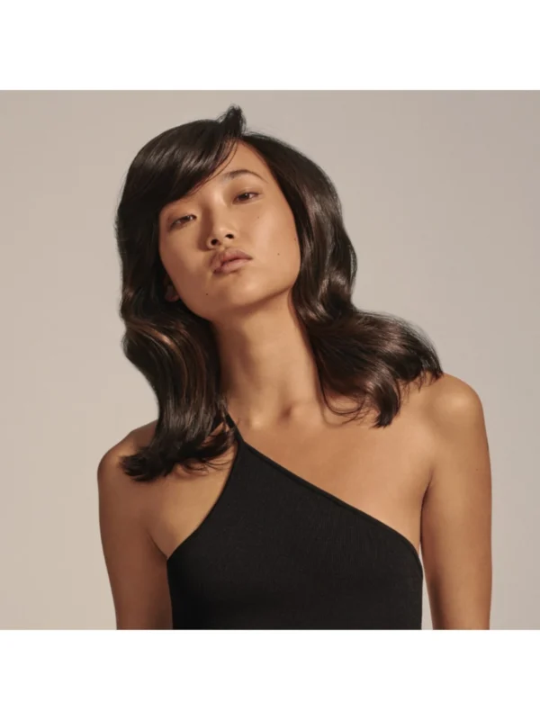 Efecto de volumen y fijación en modelo de cabello oscuro ondulado con Oribe Gold Lust Imperial Blowout