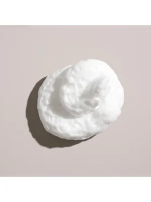 Detalle de la textura rica y cremosa de la espuma Grandiose de Oribe para un volumen majestuoso