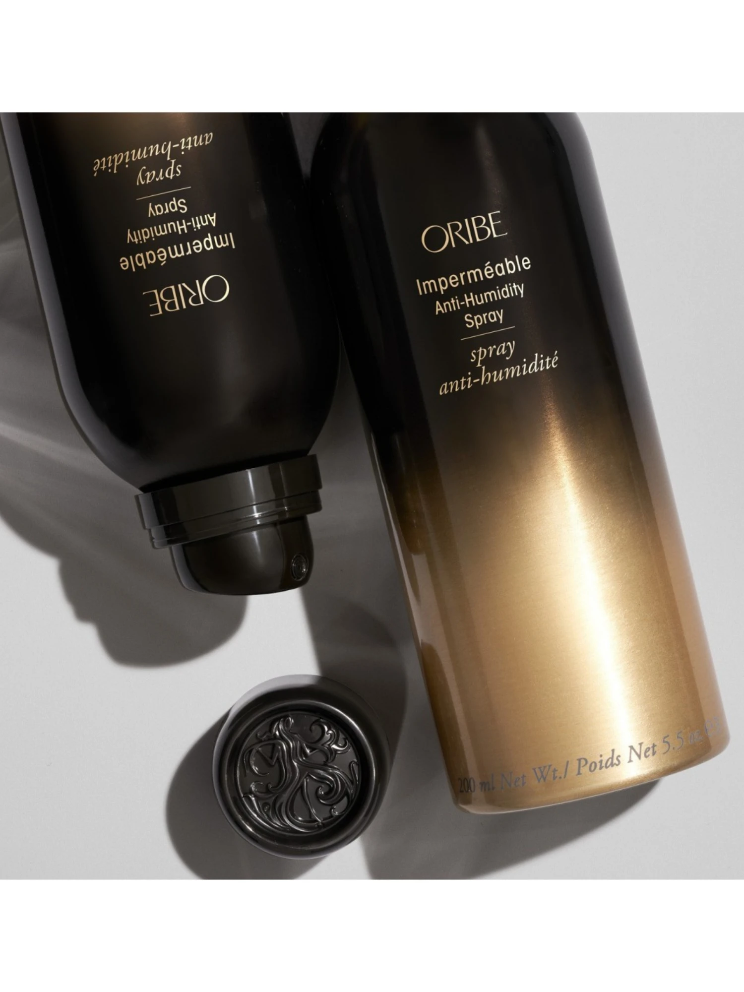 Composición estética de Oribe Impermeable Anti-Humidity Spray mostrando el difusor y detalle del tapón