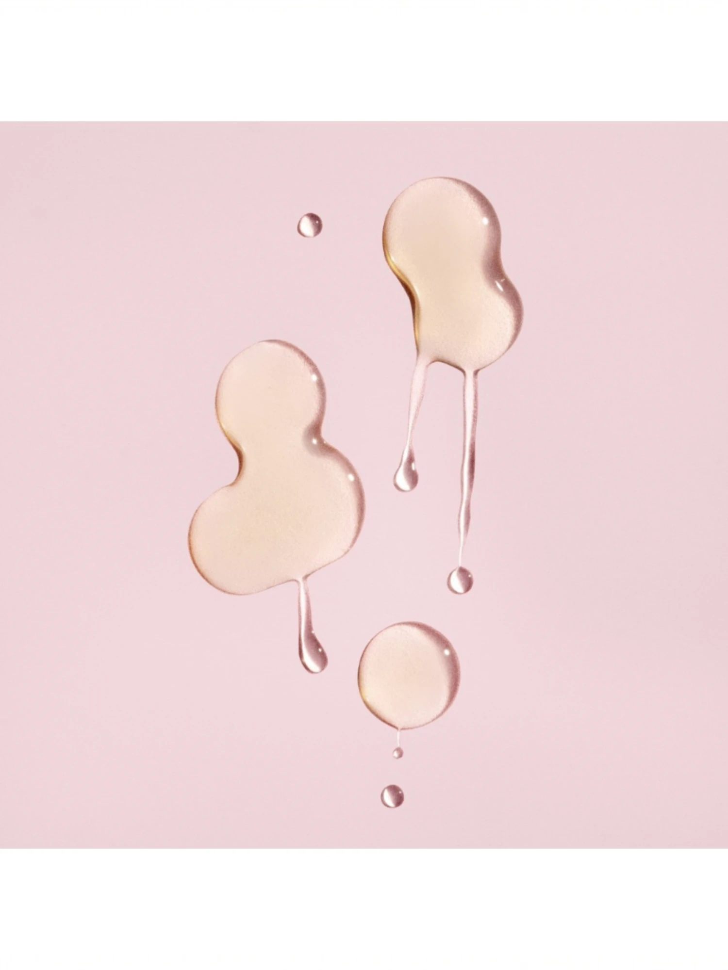 Detalle de las gotas de textura fluida y transparente del sérum protector del color de Oribe sobre fondo rosado