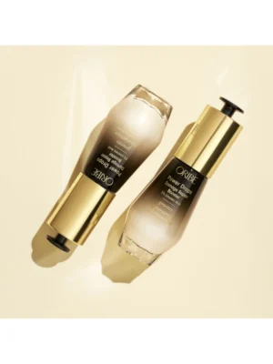 Composición estética de dos envases de Oribe Power Drops Damage Repair Booster de 30 ml junto a gotas del producto sobre fondo neutro