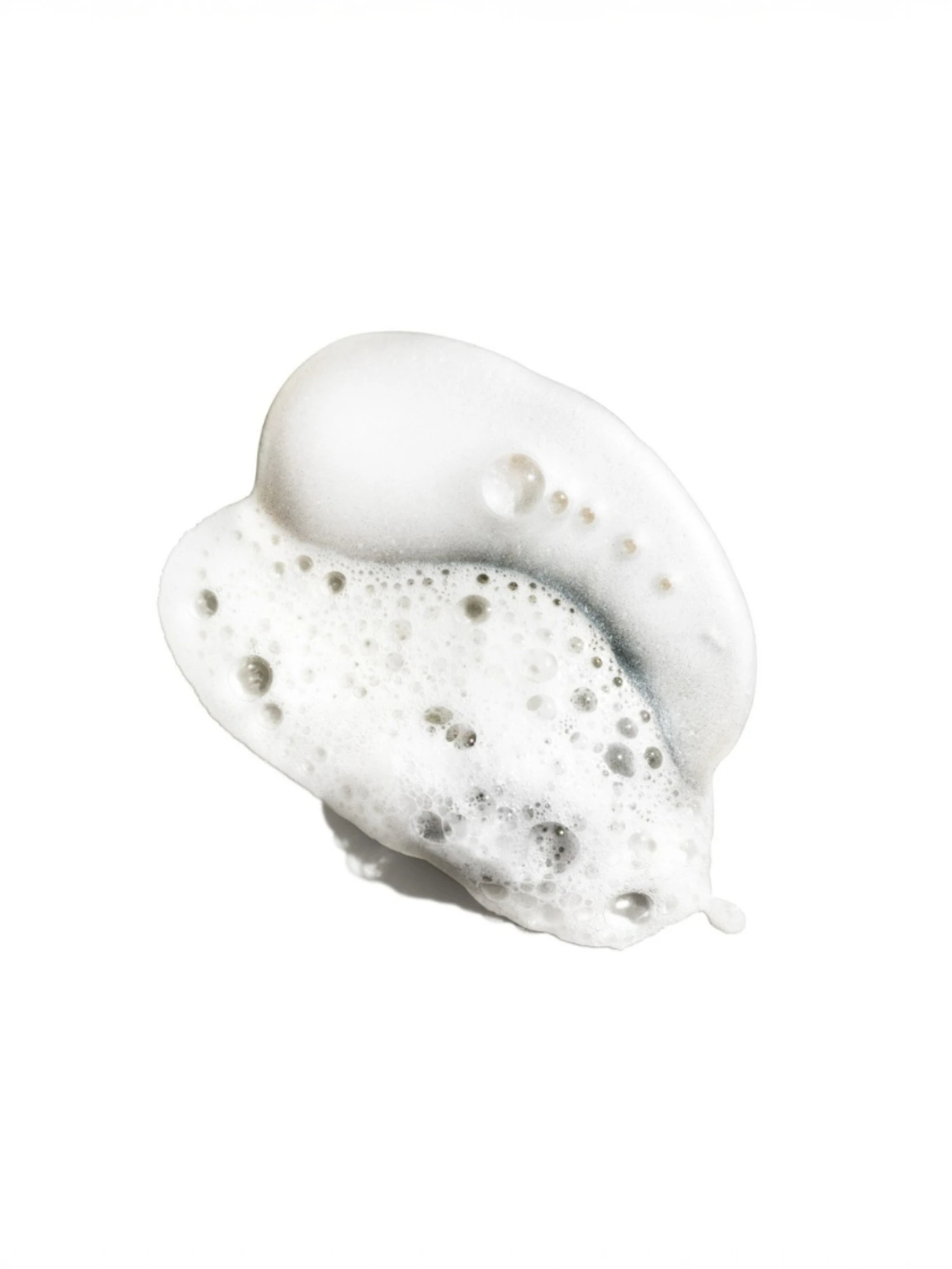 Muestra de la textura del producto en forma de espuma blanca con burbujas de distintos tamaños sobre un fondo blanco neutro.