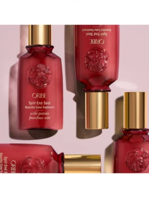 Composición estética de varios envases de Oribe Split End Seal Beautiful Color Treatment de 50 ml sobre fondo rosado