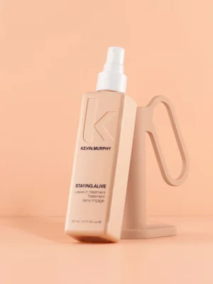 Kevin Murphy STAYING ALIVE spray leave in sobre fondo beige con packaging rosa