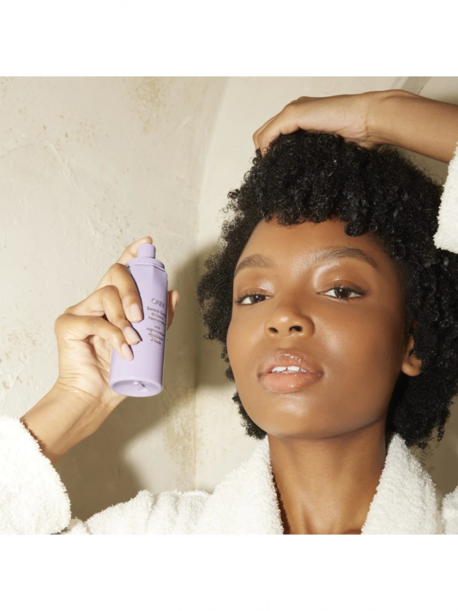 Modelo con cabello oscuro muy rizado aplicando la bruma Serene Scalp Oil Control Treatment Mist directamente sobre la raíz.