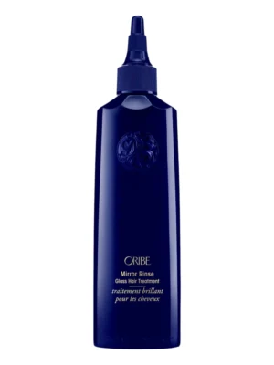 Botella frontal de Oribe Mirror Rinse Glass Hair Treatment en color azul marino brillante con aplicador de punta fina y emblema en relieve sobre fondo blanco.