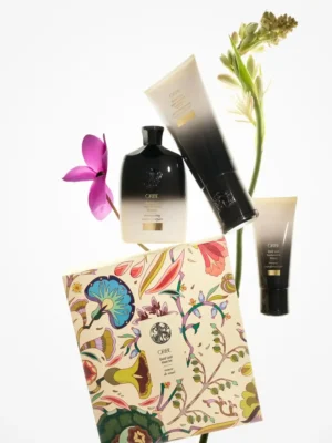 Composición artística del Oribe Gold Lust Ritual Set con productos de cuidado capilar y elementos botánicos