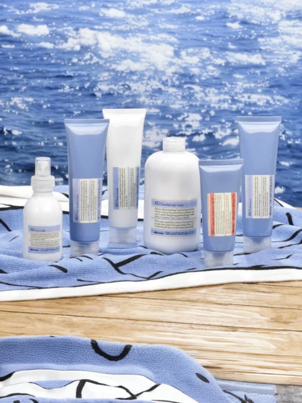 Línea completa Davines SU sobre toalla de playa: champú, mascarilla, leche protectora y aftersun para el cuidado solar integral