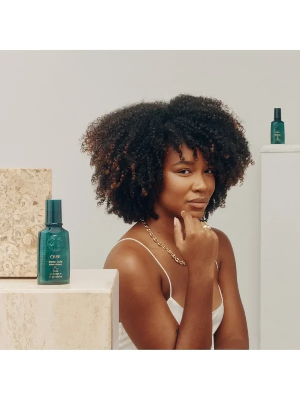 Modelo con cabello rizado definido usando Oribe Eternal Curls Polish & Protect Oil acabado brillante sin frizz