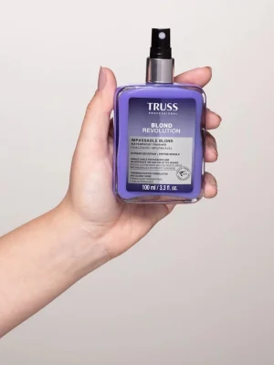 Mano sosteniendo Truss Blond Revolution Impassable Blond 100 ml spray protector para cabellos rubios