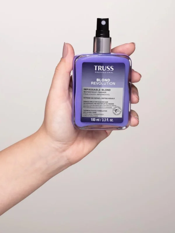 Mano sosteniendo Truss Blond Revolution Impassable Blond 100 ml spray protector para cabellos rubios