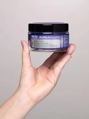 Mano sosteniendo Truss Blond Revolution Net Blond Mask 180 ml mascarilla matizadora para cabellos rubios