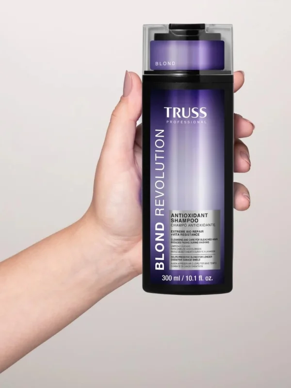 Mano sosteniendo Truss Blond Revolution Shampoo 300 ml champú antioxidante para cabellos rubios