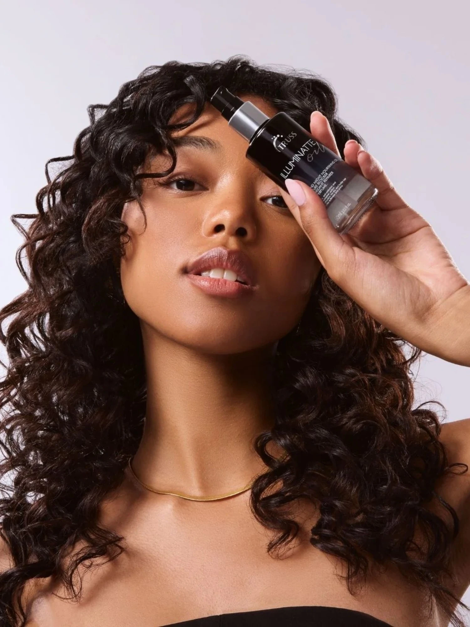 Modelo con cabello rizado sujetando Truss Illuminatte Oil