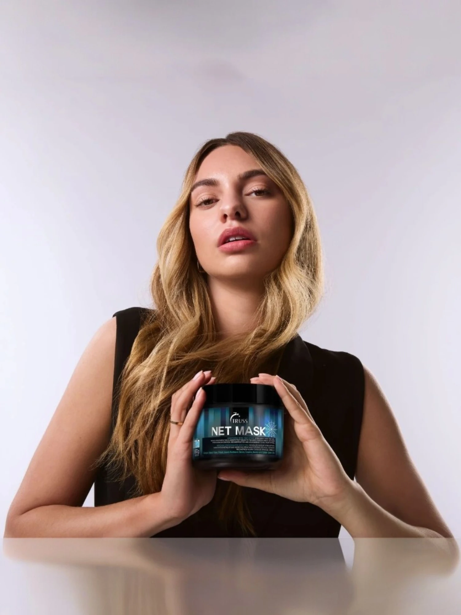 Modelo con cabello cuidado sosteniendo Truss Net Mask mascarilla capilar