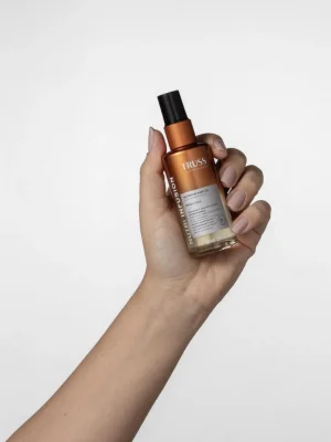 Truss Nutri Infusion Nutritive Hair Oil en la mano mostrando tamaño y formato