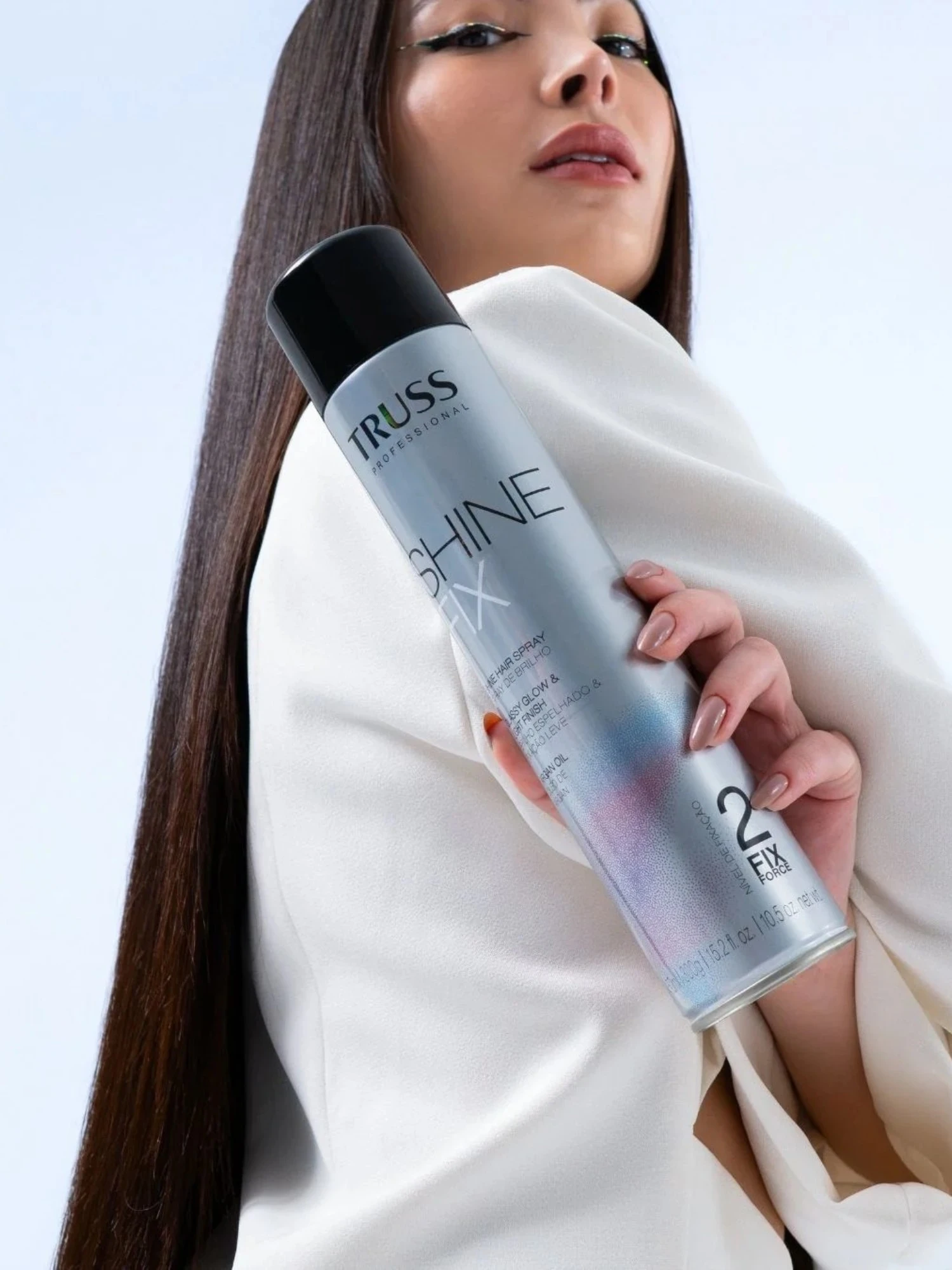 Modelo con cabello liso brillante sosteniendo spray Truss Shine Fix acabado luminoso